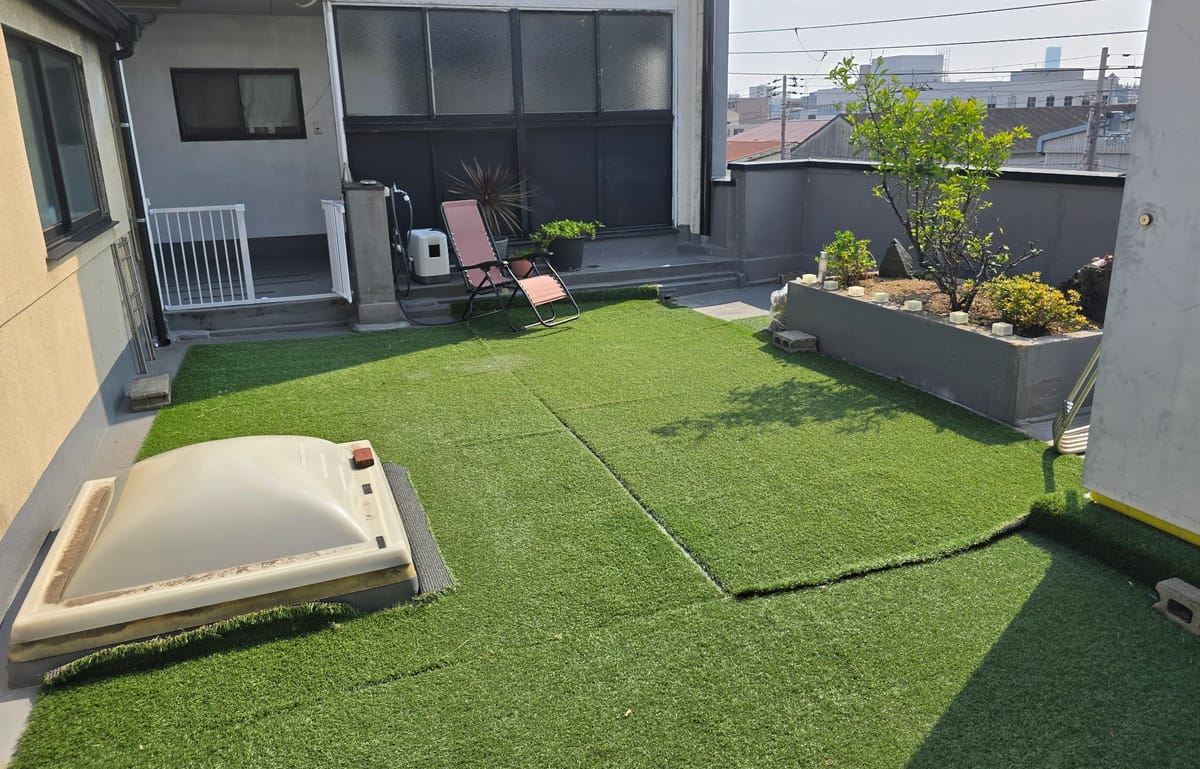 人工芝と植栽のある柵で囲まれた中庭